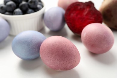 Photo of Colorful Easter eggs painted with natural dyes on white table, closeup