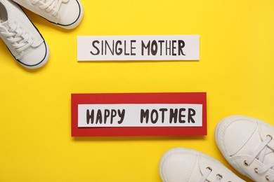 Being single mother concept. Children's and woman's gumshoes on yellow background, flat lay