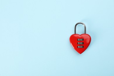 Red heart shaped combination lock on light blue background, top view. Space for text