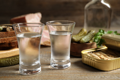 Cold Russian vodka with snacks on wooden table, closeup