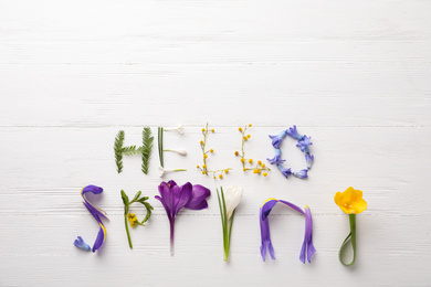 Words HELLO SPRING made of fresh flowers on white wooden table, flat lay