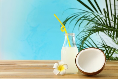 Composition with bottle of coconut water on wooden table against blue background. Space for text