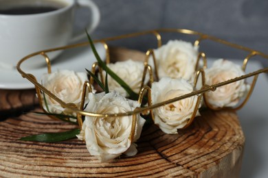 Decorative gold holder with flowers and cup of coffee on wooden stand, closeup. Interior design