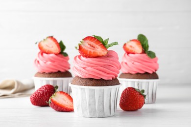 Sweet cupcakes with fresh strawberries on white table