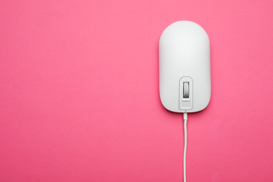 Wired computer mouse on pink background, top view. Space for text