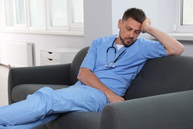 Exhausted doctor resting on sofa in hospital