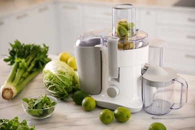 Modern juicer with fresh fruits on table in kitchen
