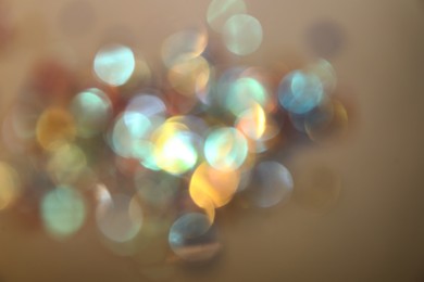 Blurred view of shiny lights on beige background. Bokeh effect