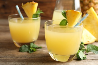 Photo of Delicious fresh pineapple juice with mint on wooden table, closeup