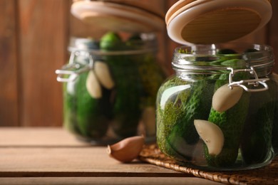 Photo of Glass jars with fresh cucumbers ready for canning on wooden table, space for text