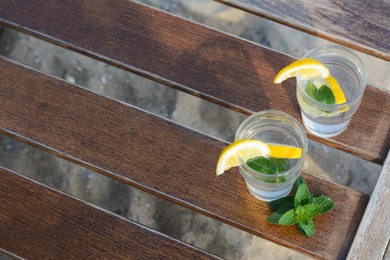 Photo of Refreshing water with lemon and mint on wooden table outdoors, above view. Space for text