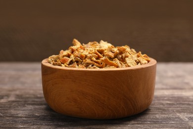 Photo of Bowl of dried orange zest seasoning on wooden table