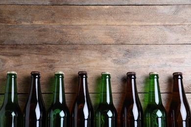 Photo of Bottles of beer on wooden table, flat lay. Space for text