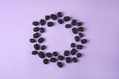 Frame made of tasty blackberries on purple background, top view with space for text