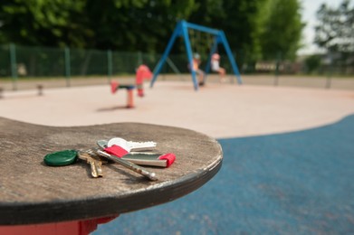 Keys forgotten on seat of spring rider at playground, space for text. Lost and found