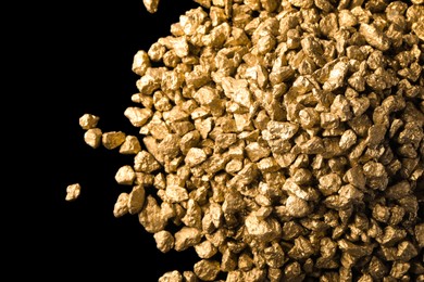 Pile of gold nuggets on black background, flat lay