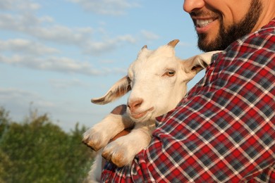 Man with baby goat at farm, closeup. Animal husbandry