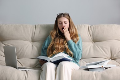 Photo of Young tired woman studying on couch indoors
