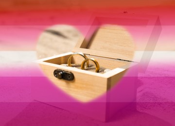 Double exposure of lesbian flag and golden wedding rings in box