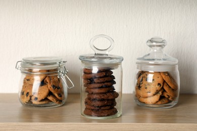 Delicious chocolate chip cookies in glass jars on wooden table