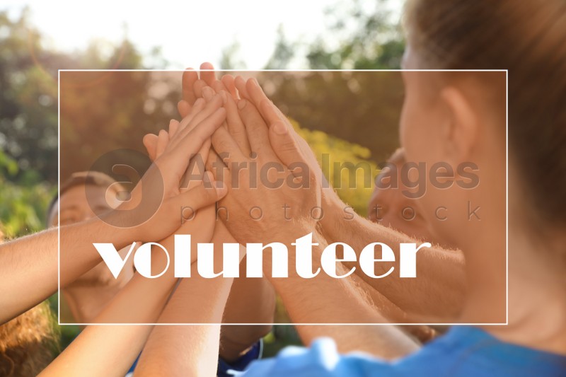 Group of volunteers putting hands together outdoors, closeup