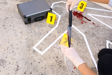 Detective collecting evidences at crime scene, closeup