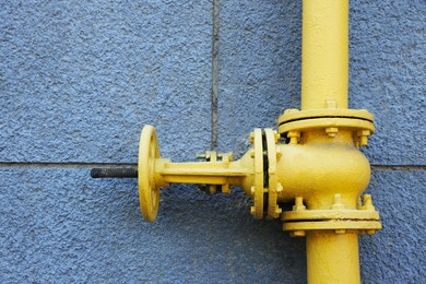 Photo of Yellow gas pipe on grey wall outdoors, closeup