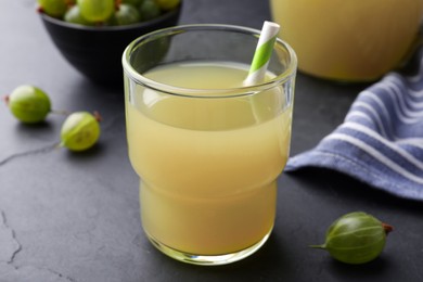 Photo of Tasty gooseberry juice in glass on black table