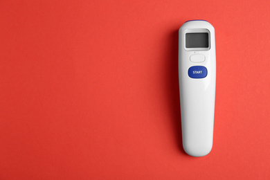 Modern non-contact infrared thermometer on red background, top view. Space for text
