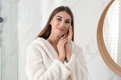 Young woman near mirror in bathroom. Skin care