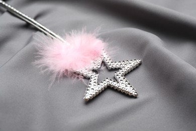Beautiful silver magic wand with feather on grey fabric, closeup