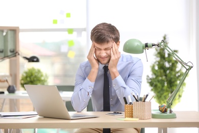 Young man suffering from headache in office