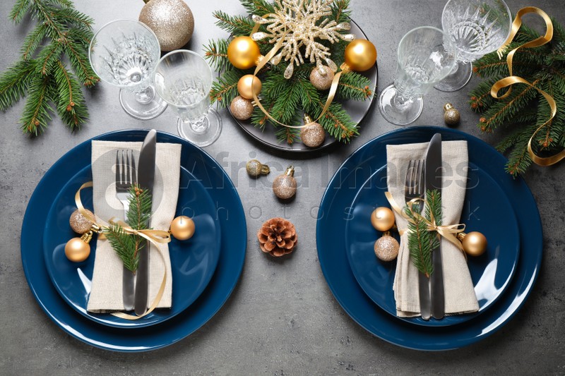 Festive table setting with beautiful dishware and Christmas decor on grey background, flat lay