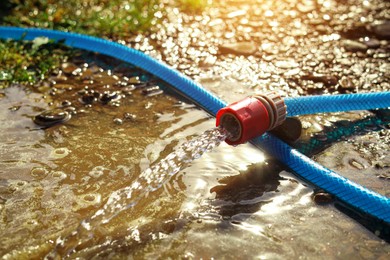 Photo of Water flowing from hose on ground outdoors, closeup. Space for text