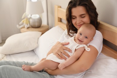 Happy young mother with her cute baby on bed at home
