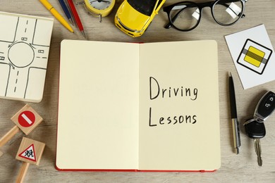 Flat lay composition with workbook for driving lessons on wooden background. Passing license exam