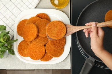 Woman cooking breaded cutlets in frying pan on stove, top view