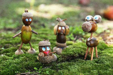 Photo of Cute figures made of acorns on green moss outdoors