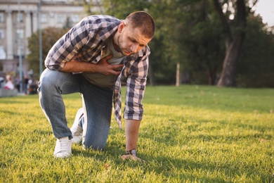 Man having heart attack on green grass in park