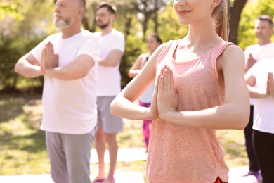 Photo of Group of people practicing yoga in park on sunny day