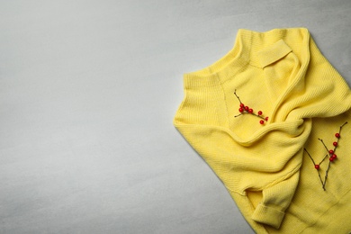 Photo of Yellow warm sweater on light grey table, top view. Space for text