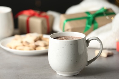 Delicious cocoa drink in white cup on grey table
