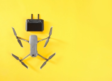 Modern drone with controller on yellow background, flat lay. Space for text