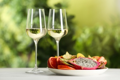 Delicious exotic fruits and wine on white table