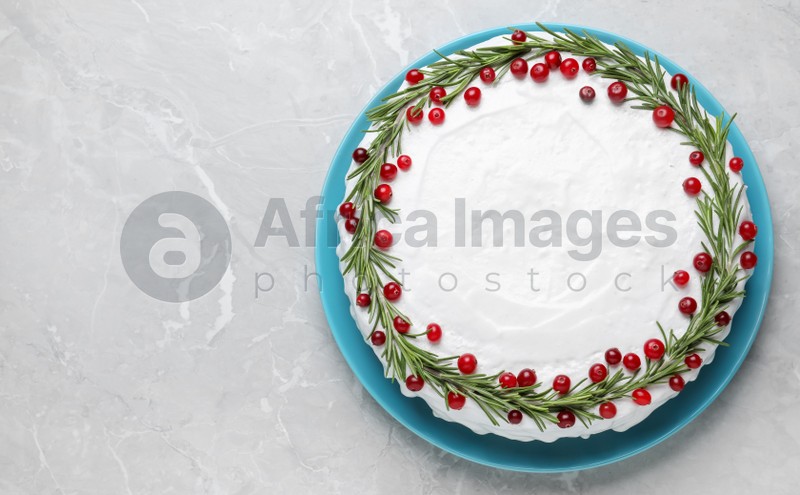 Photo of Traditional Christmas cake decorated with rosemary and cranberries on light grey marble table, top view. Space for text
