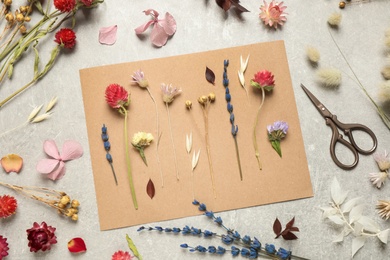 Flat lay composition with beautiful fresh and dry flowers on light grey background