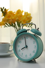 Alarm clock on white table indoors. Morning time
