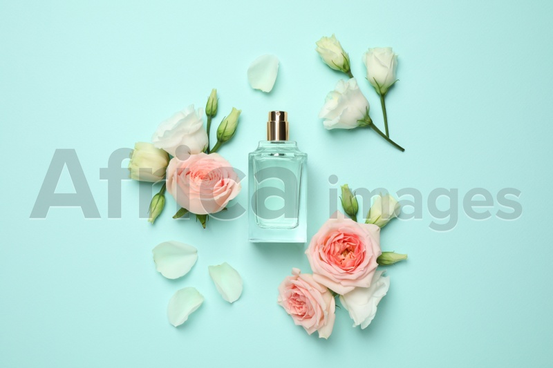 Flat lay composition with bottle of perfume and flowers on cyan background