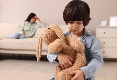 Upset child with toy bunny at home