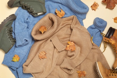 Flat lay composition with sweaters and dry leaves on beige background. Autumn season